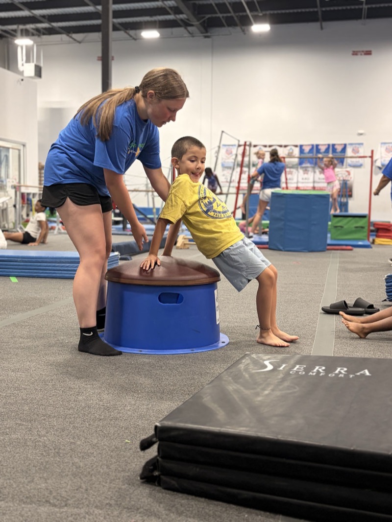A coach guiding a young athlete through a skill